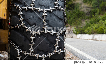 Front loader for snow removal with metal snow chains on wheels. Snow removal in the mountains. Front loader for snow removal with metal snow chains on wheels. Snow removal in the mountains. 48183077