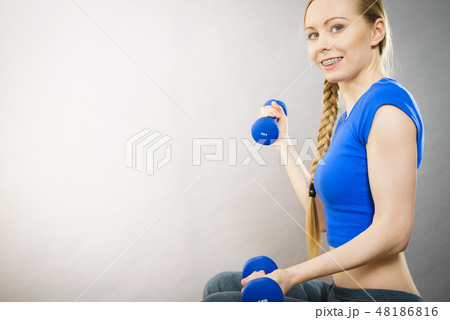 Teenage woman working out at home with dumbbell 48186816