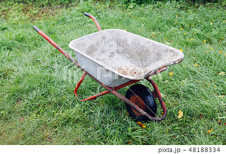 Wheelbarrow on green grass lawn in a farm garden 48188334