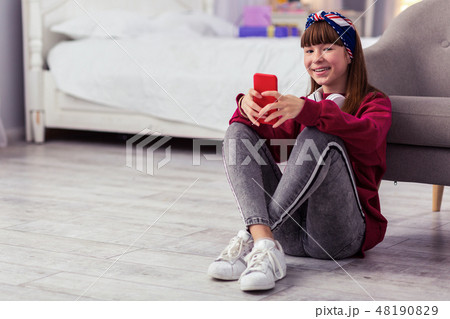 Relaxed schoolgirl crossing legs while sitting on floor 48190829