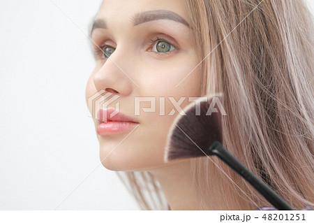 Make-up artist makes makeup beautiful blonde girl on a white background. Close-up hands with brush Make-up artist makes makeup beautiful blonde girl on a white background. Close-up hands with brush 48201251