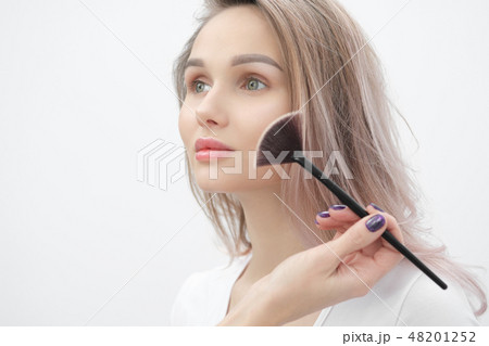 Make-up artist makes makeup beautiful blonde girl on a white background. Close-up hands with brush 48201252