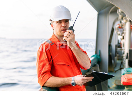 Deck Officer on deck of offshore vessel holds VHF walkie-talkie radio Deck Officer on deck of offshore vessel holds VHF walkie-talkie radio 48201607