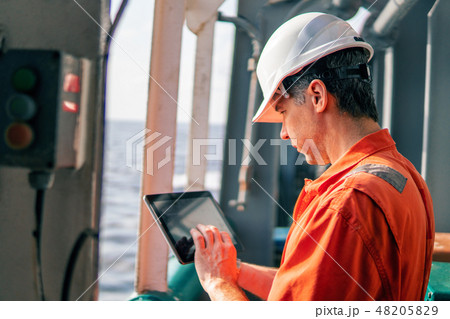 chief officer or captain on deck of vessel or ship watching digital tablet chief officer or captain on deck of vessel or ship watching digital tablet 48205829
