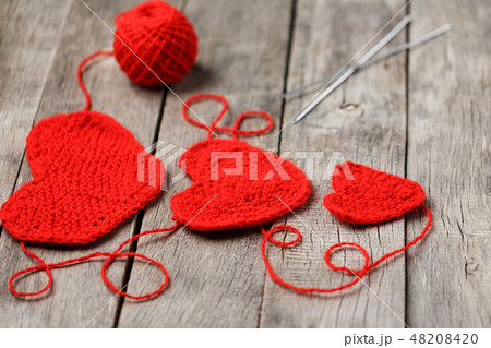 Three red knitted hearts on a gray wooden back Three red knitted hearts on a gray wooden back 48208420