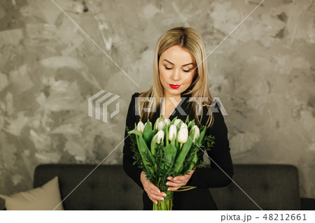 Beautiful mother hold a bouquet of white tulips on 8th of march. Flowers in woman's hand. Blond hair 48212661