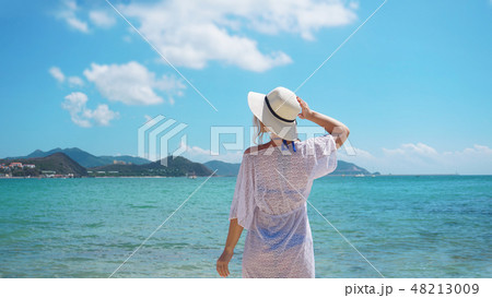 Woman in summer vacation wearing straw hat and beach dress at the ocean 48213009