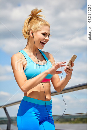 Sporty woman on pier over river holding phone 48214229