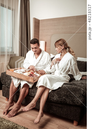 Couple wearing hotel bathrobes sitting on hotel bed 48218317
