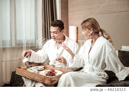 Blonde-haired wife wearing white bathrobe talking to husband Blonde-haired wife wearing white bathrobe talking to husband 48218323