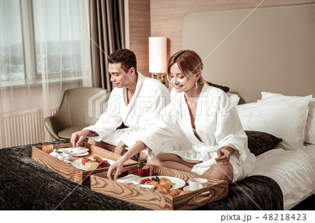 Businessmen feeling relaxed while having breakfast in bed Businessmen feeling relaxed while having breakfast in bed 48218423
