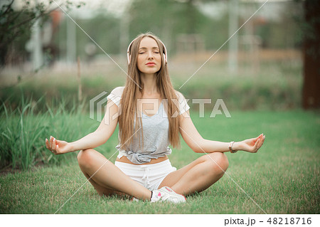 Young sportive girl doing yoga meditation in park in the city 48218716