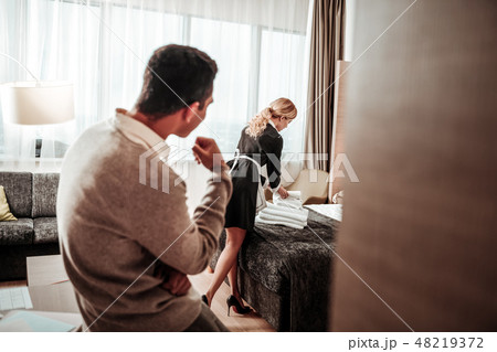 Maid working in room while client standing and watching her 48219372