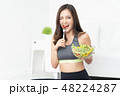 Young Asian woman is resting and eating a healthy salad after a 48224287