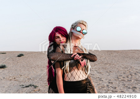 Two young sexy woman wearing leather suits hugging in the dessert Two young sexy woman wearing leather suits hugging in the dessert 48224910