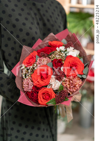 beautiful fresh cut bouquet of mixed flowers in woman hand. the work of the florist at a flower shop beautiful fresh cut bouquet of mixed flowers in woman hand. the work of the florist at a flower shop 48225234