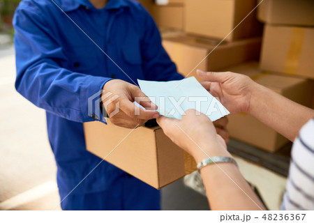Delivery man giving paper to woman 48236367