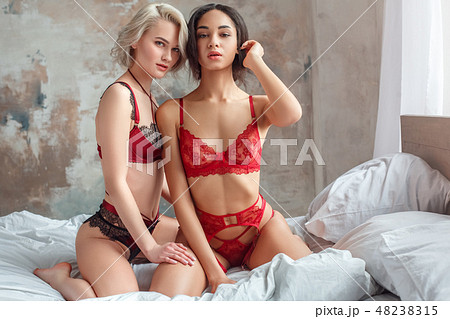 Beauty. Two women on bed wearing lingerie - Stock Photo