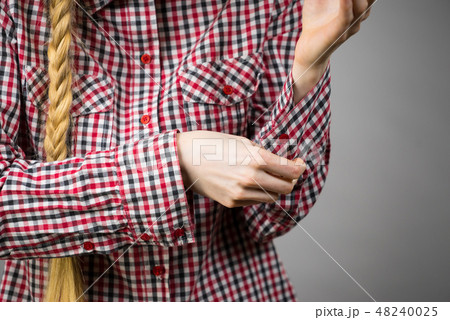 Woman rolling up the sleeves in checked shirt Woman rolling up the sleeves in checked shirt 48240025