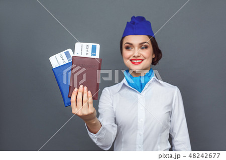 Professional Occupation. Stewardess standing isolated on grey with passports and tickets close-up Professional Occupation. Stewardess standing isolated on grey with passports and tickets close-up 48242677