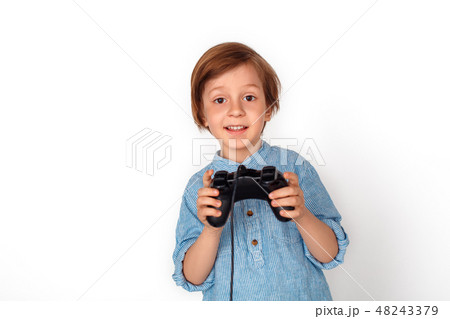 Boy studio standing isolated on grey with game controller playing game excited 48243379