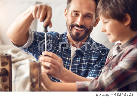 Father and little son at home standing dad screwing screw laughing happy looking at boy holding Father and little son at home standing dad screwing screw laughing happy looking at boy holding 48243523
