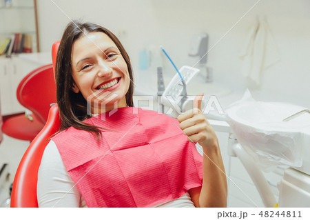 Portrait of a happy dentist in a dentist's chair. During this smiles and shows a gesture with a Portrait of a happy dentist in a dentist's chair. During this smiles and shows a gesture with a 48244811