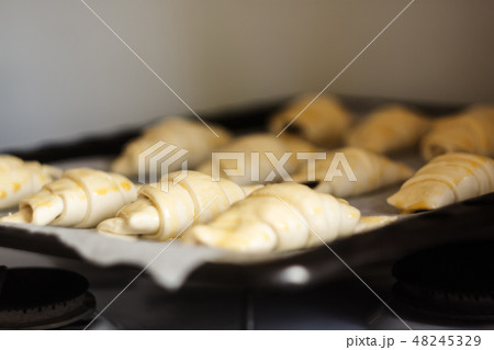 Raw croissants with chocolate on a baking sheet before baking Raw croissants with chocolate on a baking sheet before baking 48245329