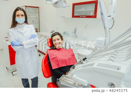 Dentist and patient. Young beautiful dentist repairing teeth of a beautiful young woman in the 48245575