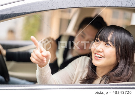 ドライブデートで雨上がりの虹を見つけて嬉しそうな顔をする可愛い女性を運転席から覗き込むイケメン男性の写真素材 4457