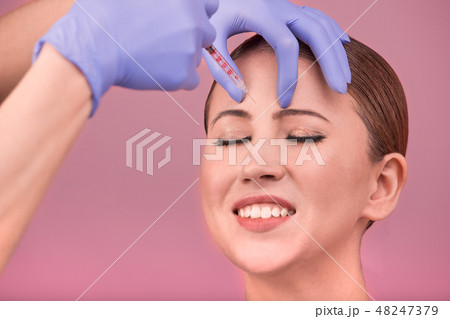 Beautiful woman face and beautician hands with syringe. Doctor makes cosmetic injection in the upper 48247379