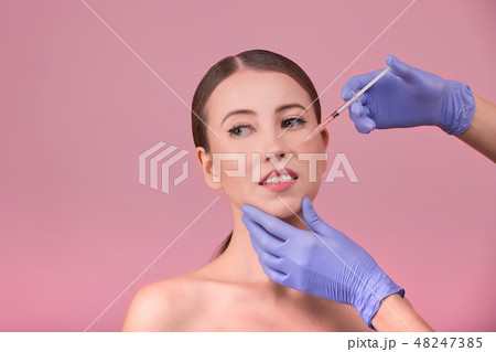 Beautiful woman face and beautician hands with syringe. Doctor makes cosmetic injection in the upper Beautiful woman face and beautician hands with syringe. Doctor makes cosmetic injection in the upper 48247385
