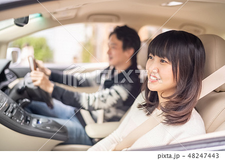 安全運転で真面目な彼の車でリラックスして旅行を楽しむ若い女性の写真素材