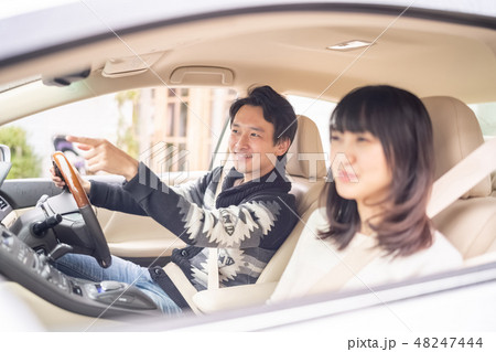 運転しながら彼女のお気に入りの店を見つけ得意げに話すイケメン男性 48247444