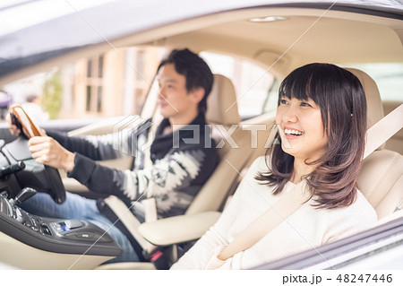 安全運転で真面目な彼の車でリラックスして旅行を楽しむ若い女性の写真素材