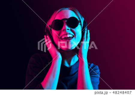 Fashion pretty woman with headphones listening to music over neon background 48248407