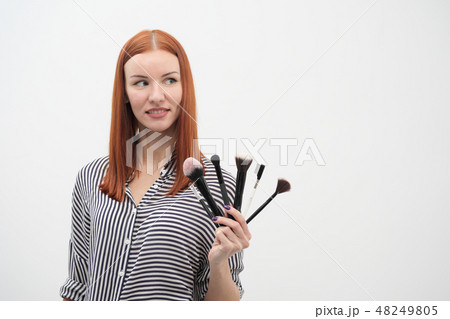 Portrait of a red-haired girl, make-up of actor, professional on white background. Paint brushes and 48249805