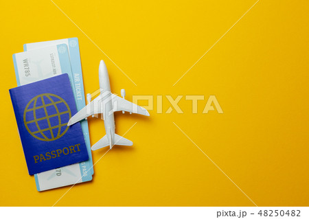 Tickets for plane and passport with model of passenger plane on yellow background. Copy space for Tickets for plane and passport with model of passenger plane on yellow background. Copy space for 48250482