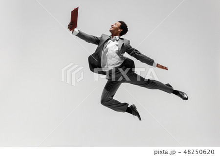 Happy businessman dancing isolated on gray studio background 48250620