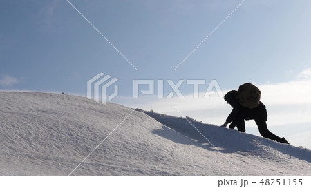 climbers hand in hand climb to top of a snowy mountain. the team of travelers in winter go to their climbers hand in hand climb to top of a snowy mountain. the team of travelers in winter go to their 48251155