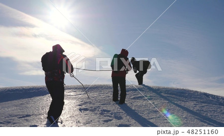 three Alpenists climb rope on snowy mountain. Tourists work together as team shaking heights 48251160