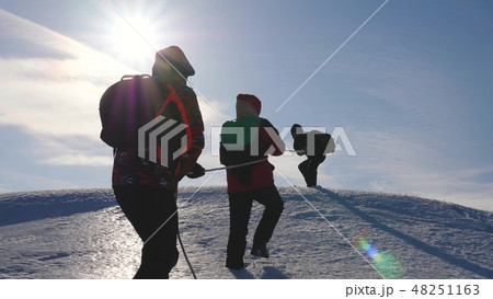 three Alpenists climb rope on snowy mountain. Tourists work together as team shaking heights three Alpenists climb rope on snowy mountain. Tourists work together as team shaking heights 48251163