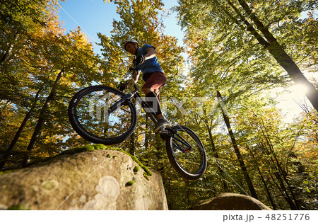 Professional sportsman cyclist jump on trial bike on boulder 48251776