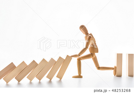 Wooden mannequin stopping domino effect on white 48253268