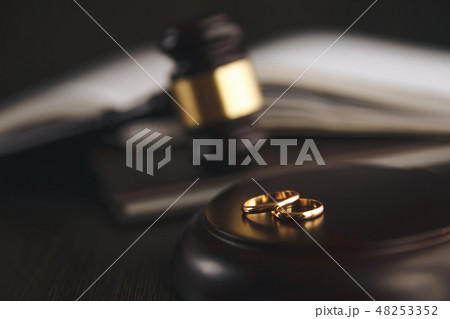 Wedding rings on the figure of a broken heart from a tree, hammer of a judge on a wooden background Wedding rings on the figure of a broken heart from a tree, hammer of a judge on a wooden background 48253352