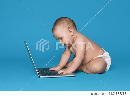 Adorable baby working on laptop on blue studio background Adorable baby working on laptop on blue studio background 48253353