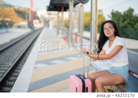 Young Beautiful Asian Tourist Woman Sitting While Waiting At The Train Station Young Beautiful Asian Tourist Woman Sitting While Waiting At The Train Station 48255170