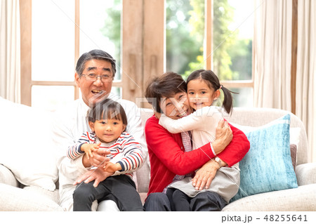 お正月じいちゃんばあちゃんに会いに実家に帰省する孫を抱きしめて嬉しそうな祖父母 48255641