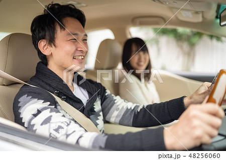 新居を探しに期待を胸に笑顔で車を走らせる新婚カップル男女二人の写真素材