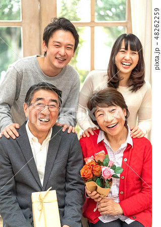 父の日母の日花束プレゼント親孝行な息子娘夫婦笑顔が絶えない家庭仲良し家族の見本の写真素材